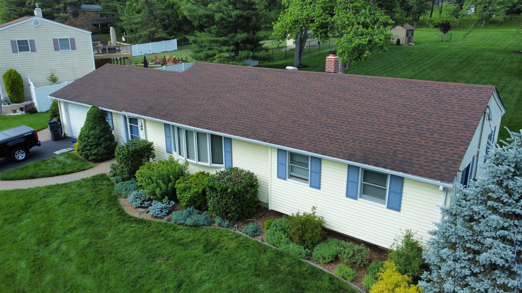 Before, from the air: the full front elevation in its original pale yellow siding under the old brown roof