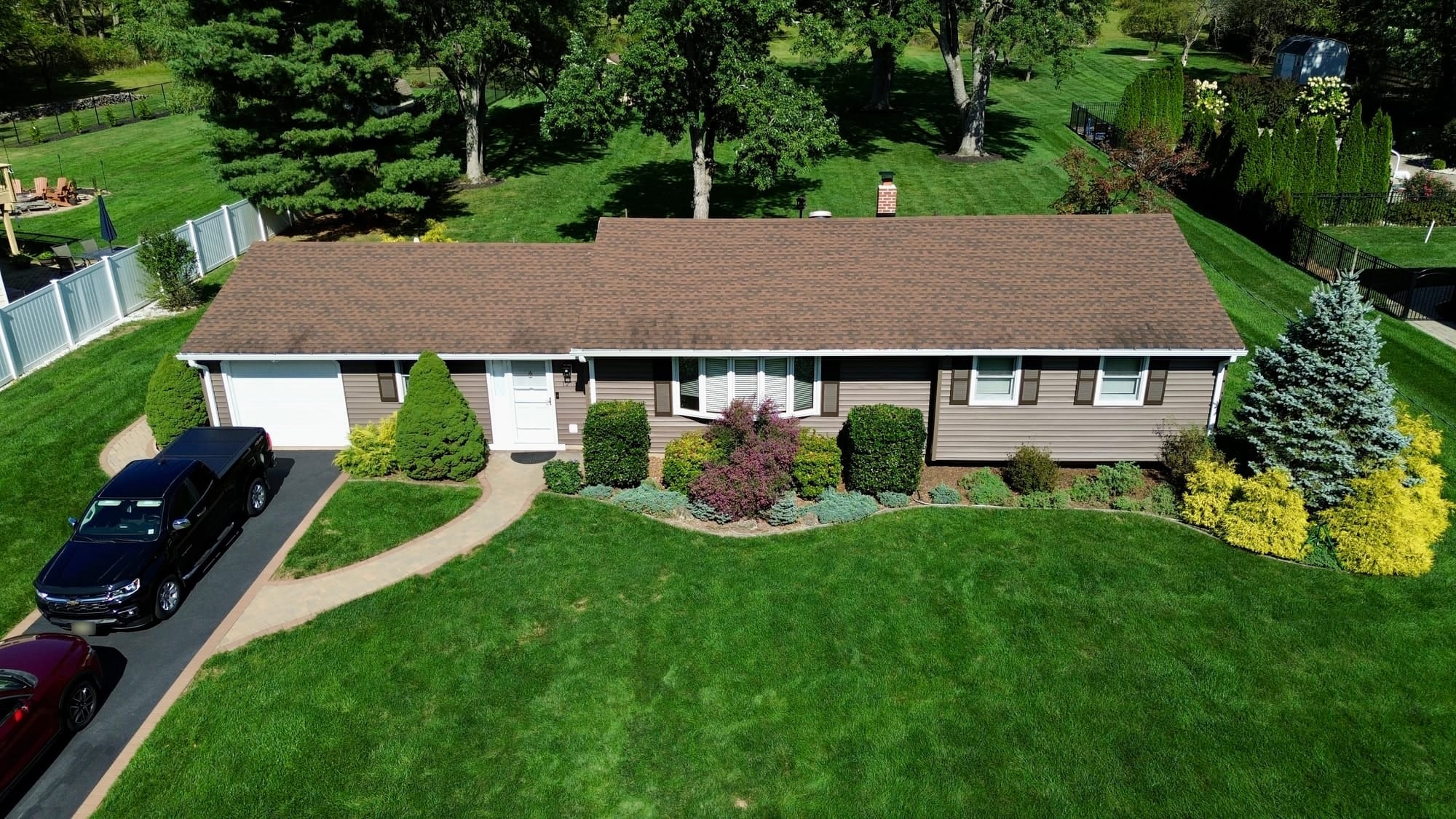 After: drone front-quarter of the whole house, new siding and gutter run reading as one continuous line