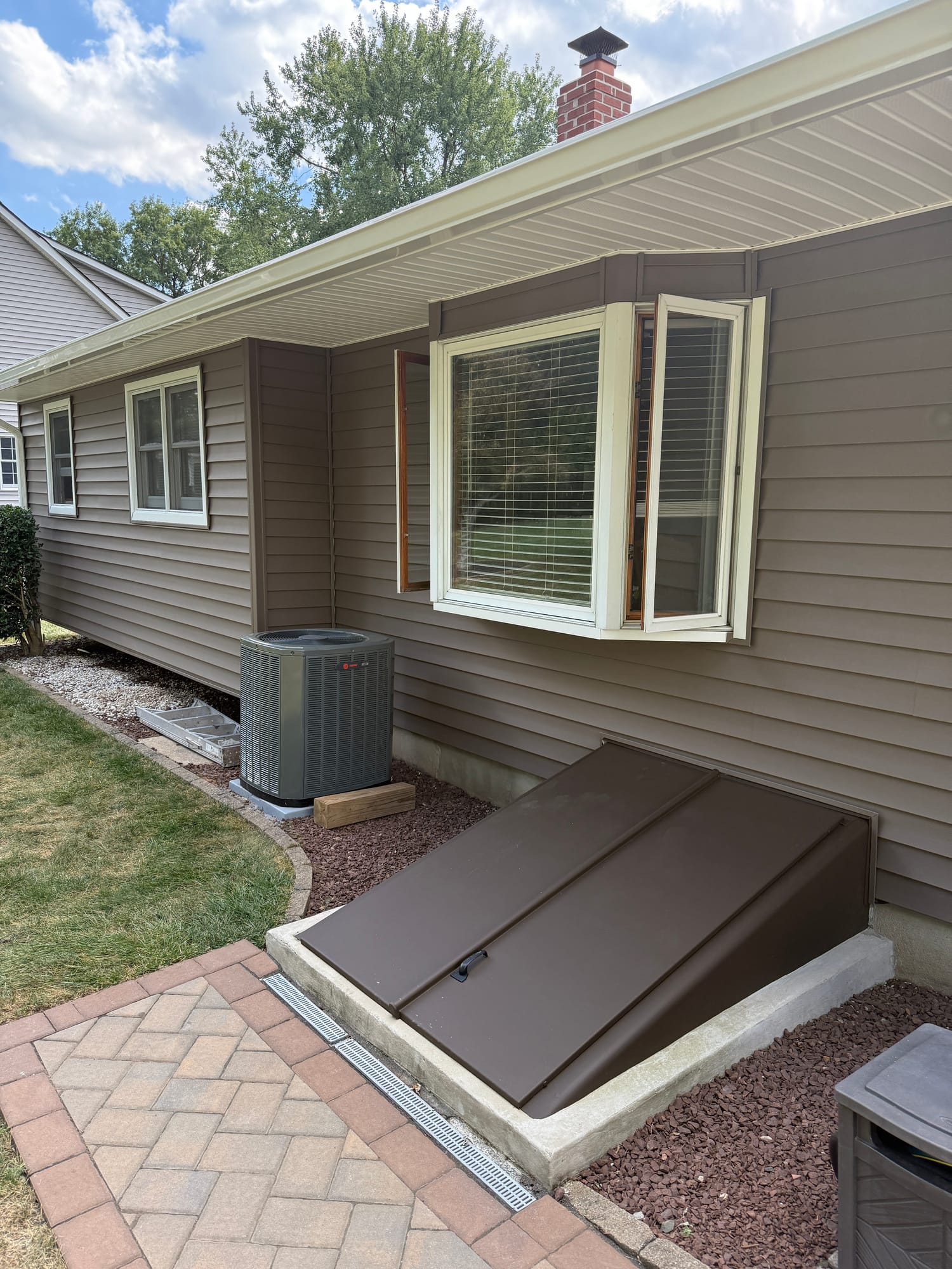 After: bay window in new cream trim wrap, siding coursed tight to head and sill, cellar bulkhead repainted to match