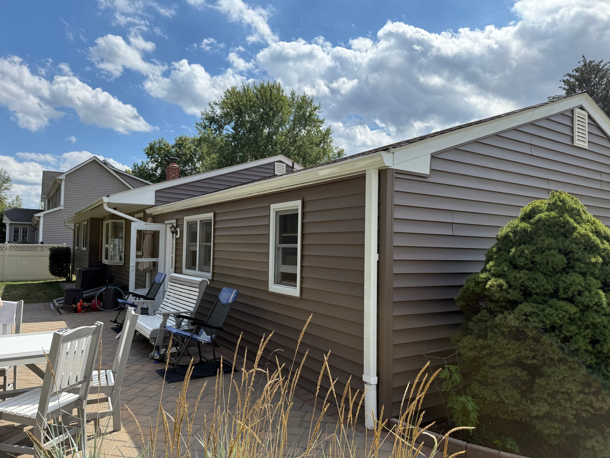 After: rear elevation over the paver patio, new siding and cream-wrapped trim carried around the return