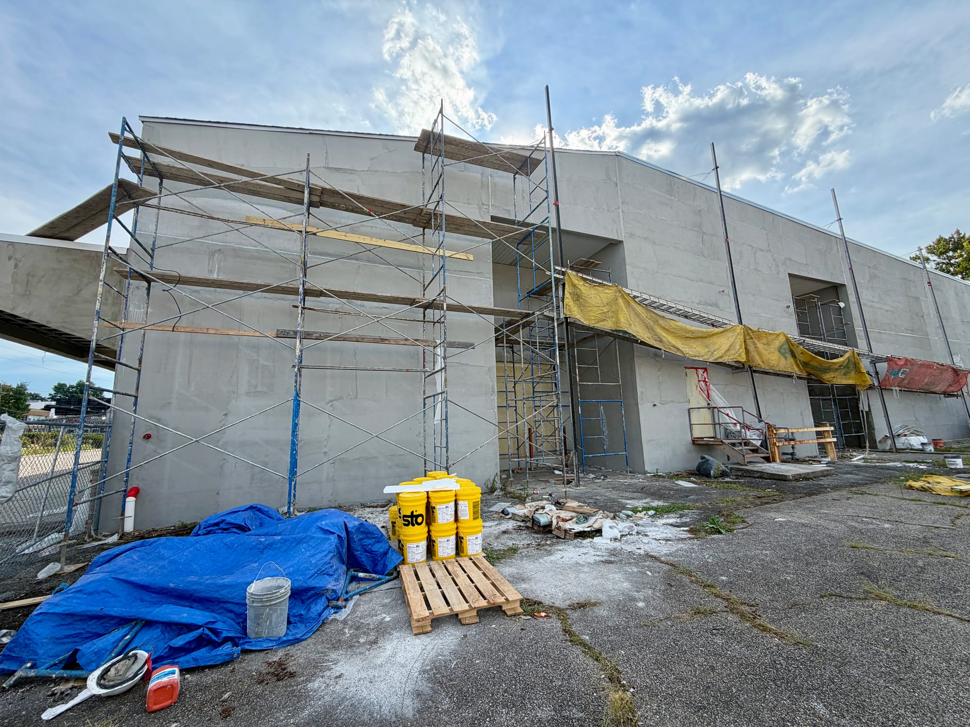Scaffold returning around the corner of the anchor building, materials and mixing station set out below