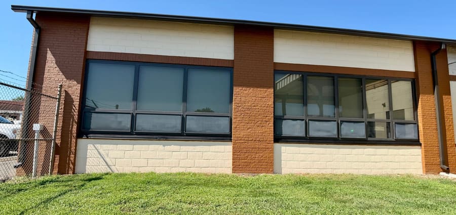 The finished side elevation of a New Jersey Department of Transportation building in Ewing. New coating carried across the cream block field between terracotta brick piers, with the window band resealed the full length of the wall.