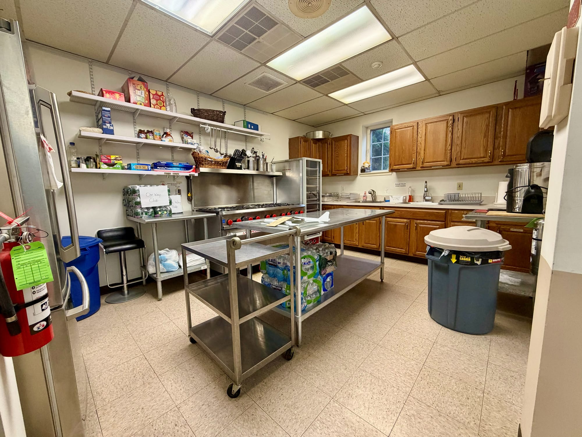 Before: commercial kitchen with original oak wall cabinets, stainless prep table and range