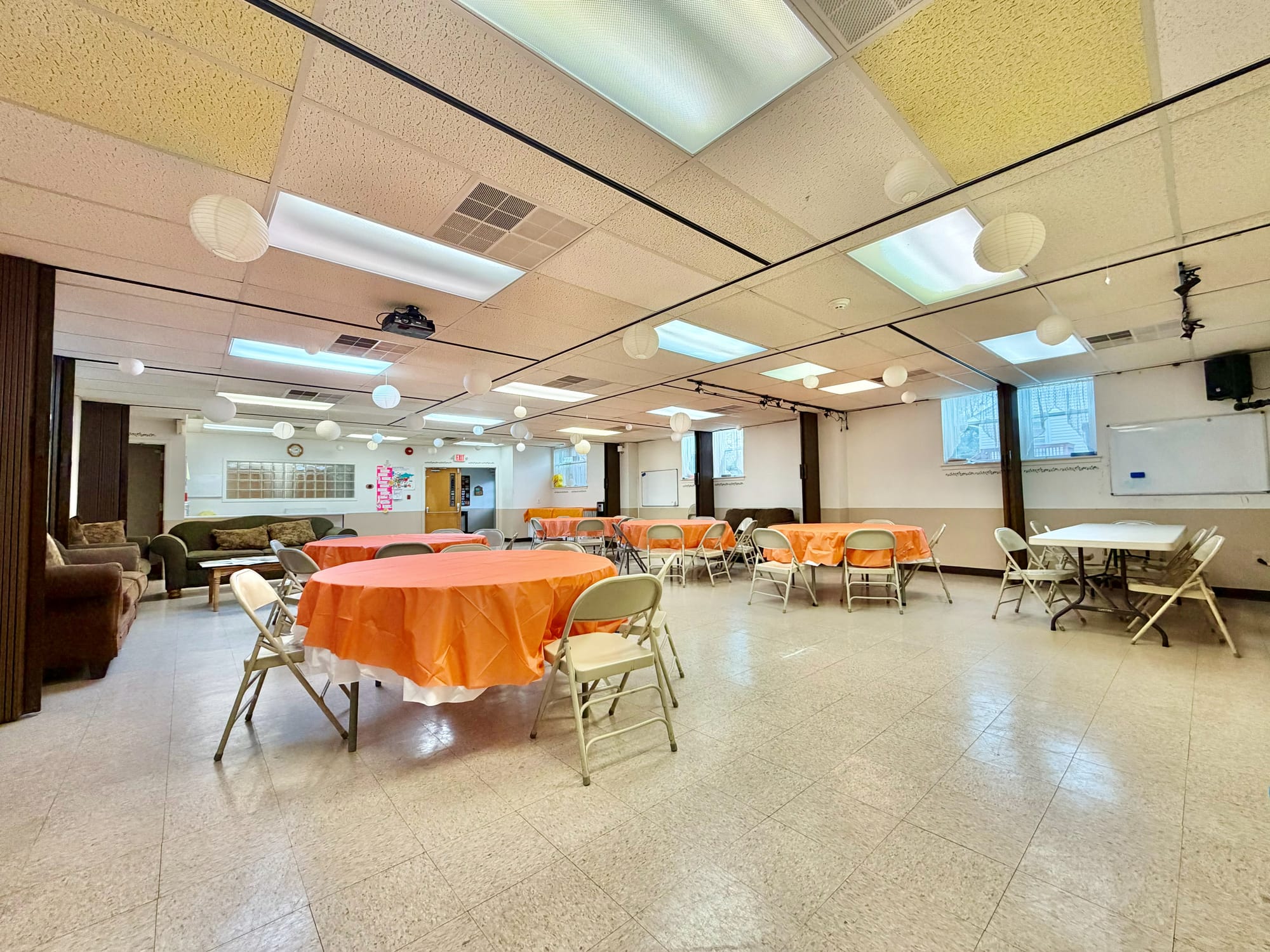 Before: speckled VCT floor, yellowed and mismatched ceiling tile, folding tables under fluorescent troffers