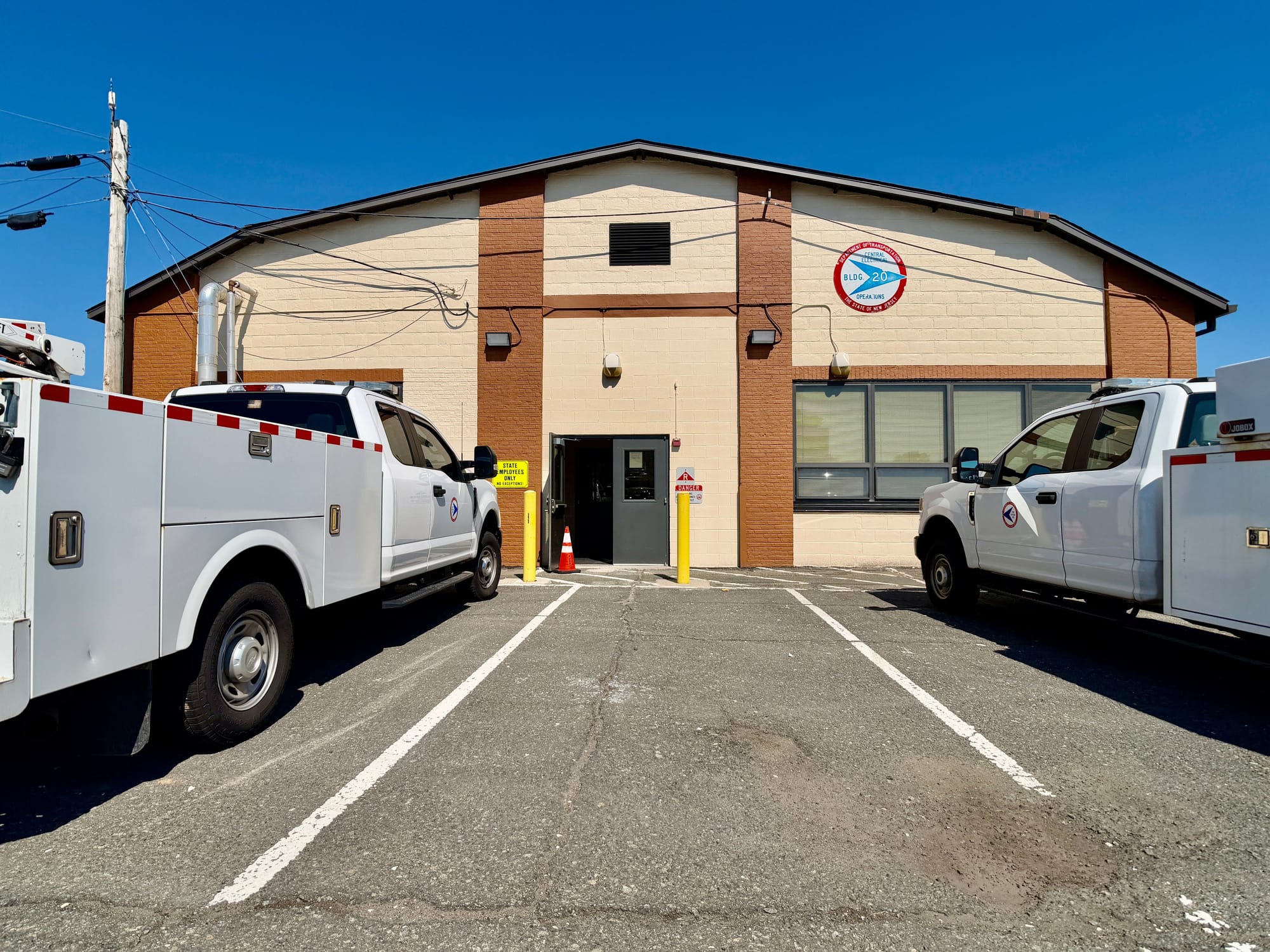 After: the finished front elevation, recoated block and brick piers with the Department's painted seal on the gable, the Department's own service vehicles parked at the entrance