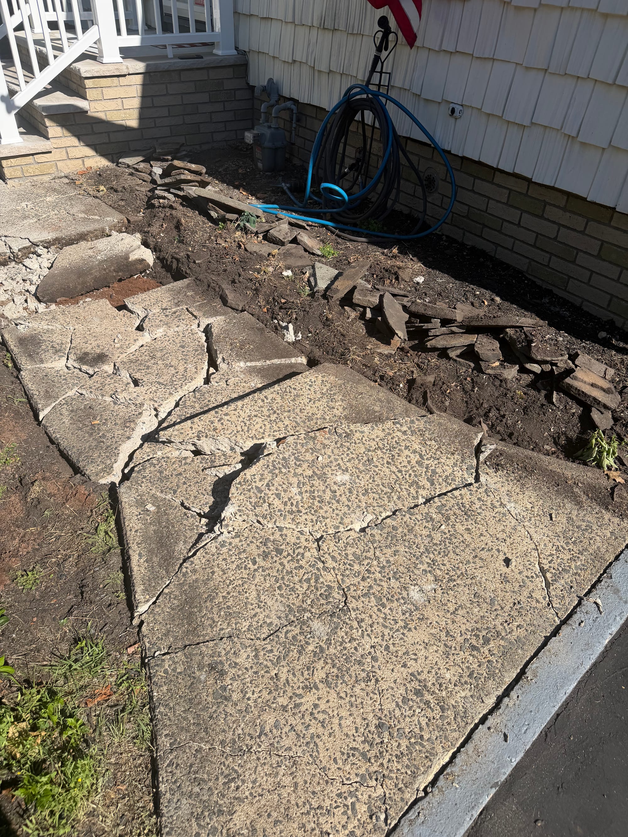 Before: the original concrete walk broken up in place, slabs lifted and the sub-base opened alongside the house