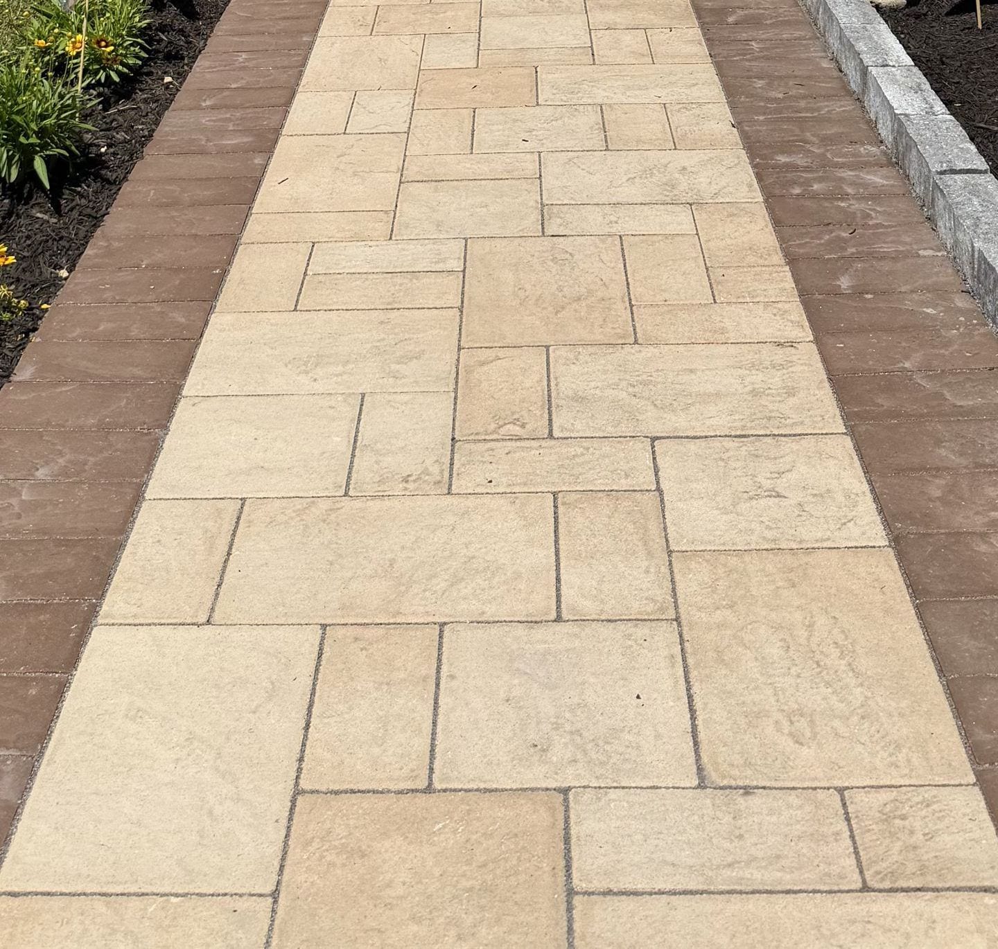 Finished paver walk with a contrasting soldier-course border either side, running between the planting bed and the stone edging