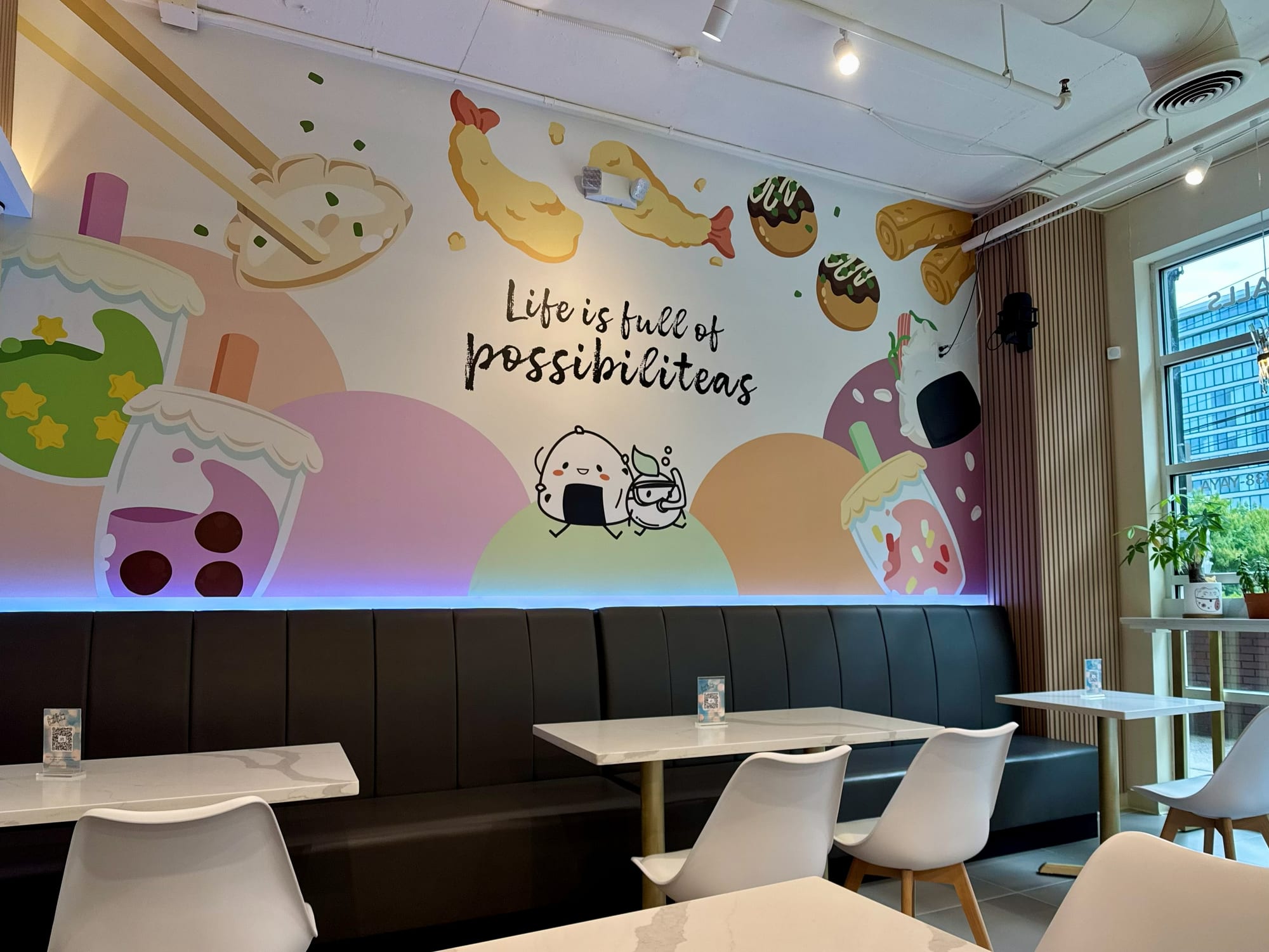 Mural above a dark upholstered banquette with LED cove wash and loose tables